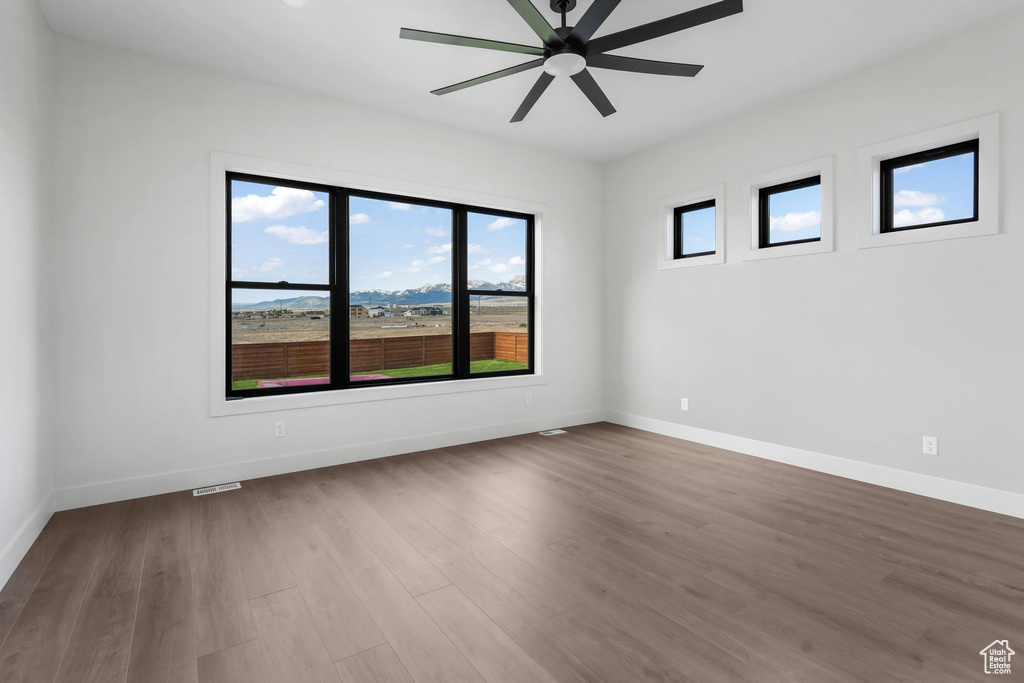 Spare room with ceiling fan, dark wood-style flooring, and baseboards