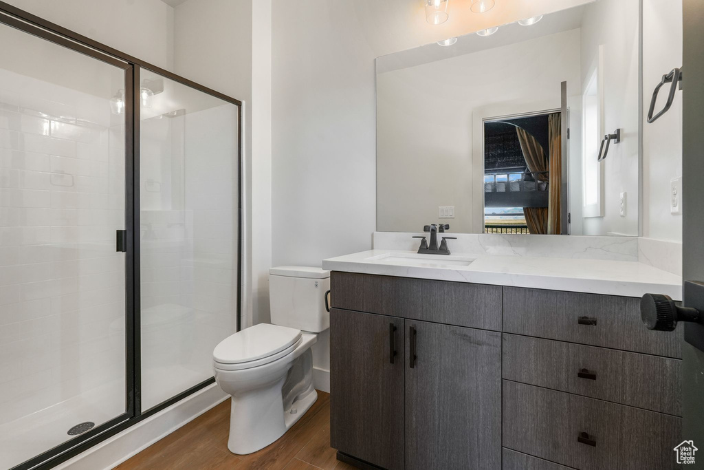 Bathroom featuring toilet, wood finished floors, vanity, and a shower stall