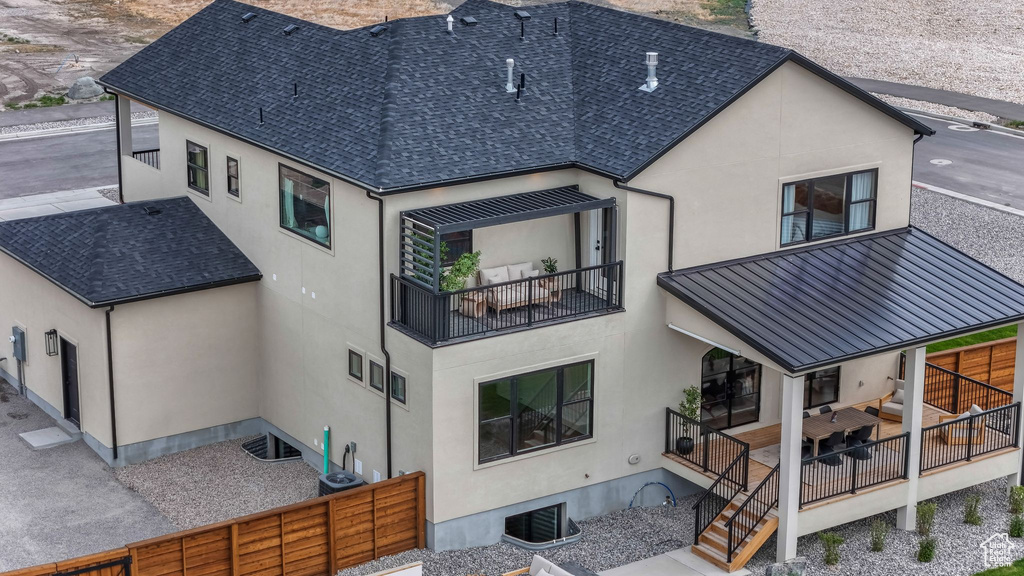 Rear view of house featuring stucco siding, a standing seam roof, metal roof, and roof with shingles