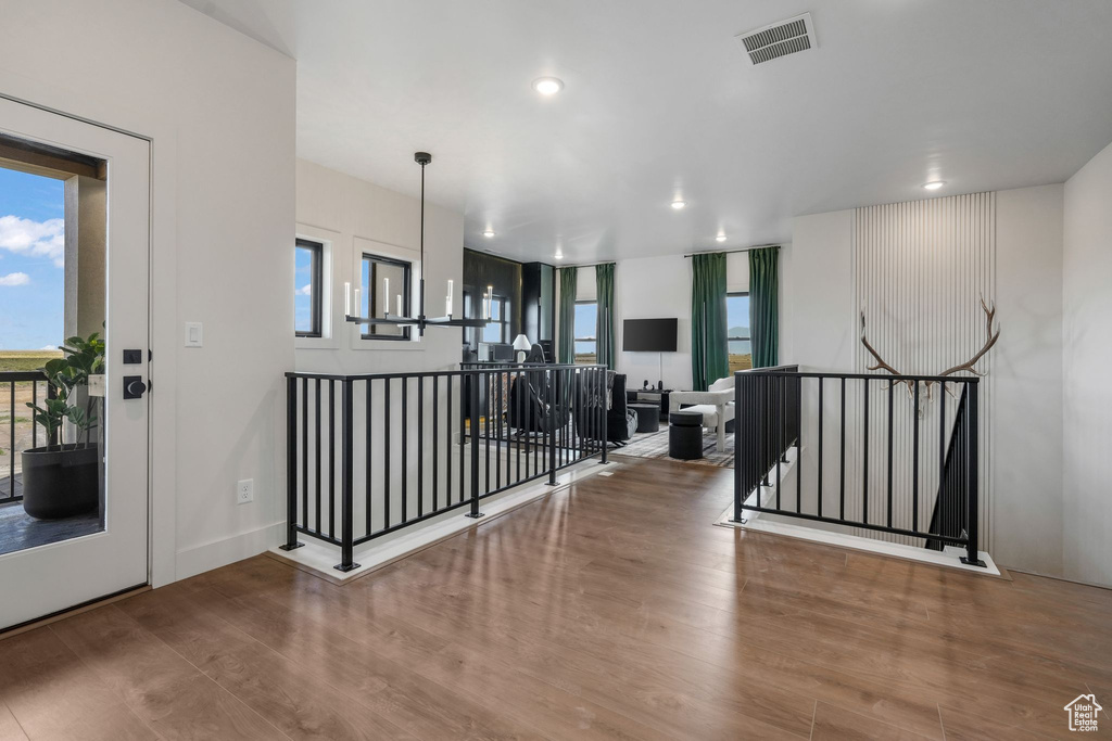 Corridor with an upstairs landing, wood finished floors, healthy amount of natural light, and recessed lighting