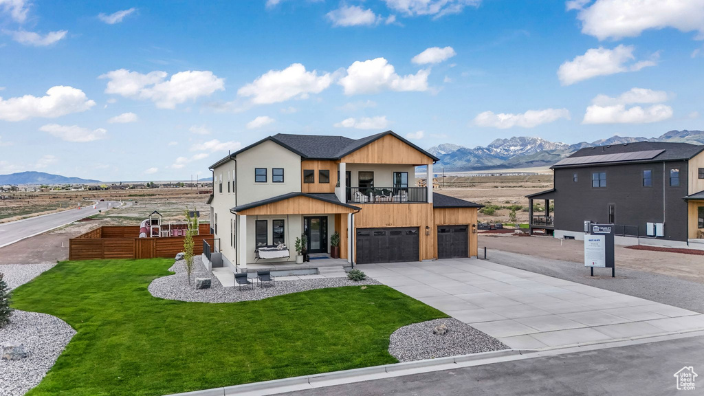 Modern home featuring a mountain view, a balcony, concrete driveway, an attached garage, and stucco siding