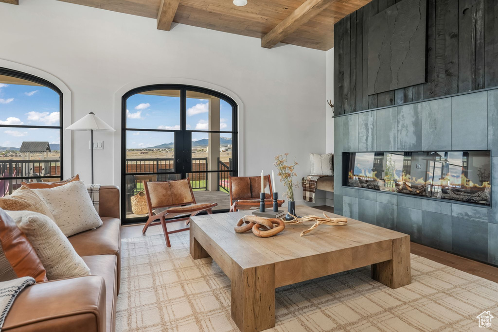 Living room with wooden ceiling with exposed beams, a high ceiling, and wood finished floors