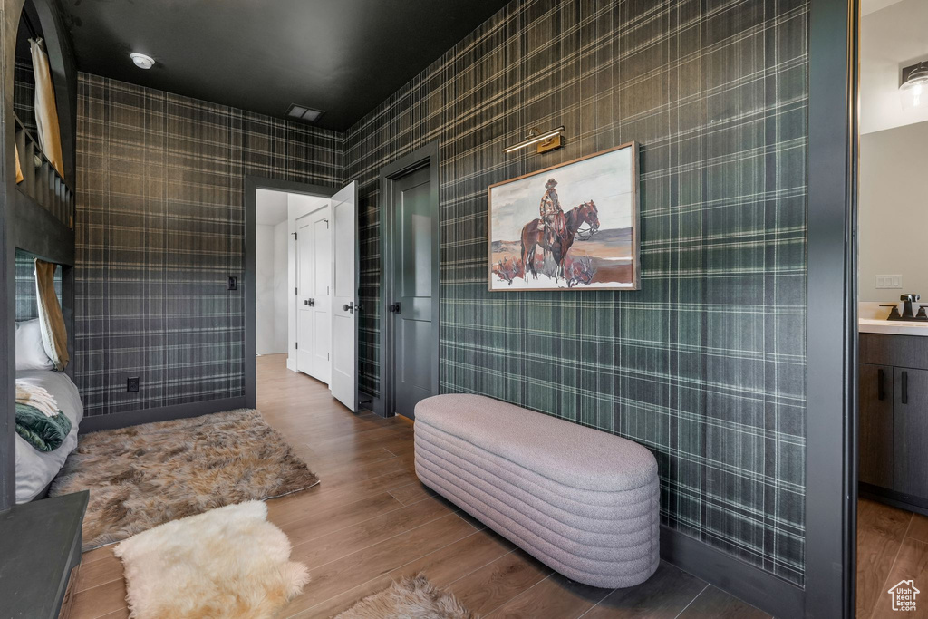 Bathroom with wood finished floors, wallpapered walls, and vanity