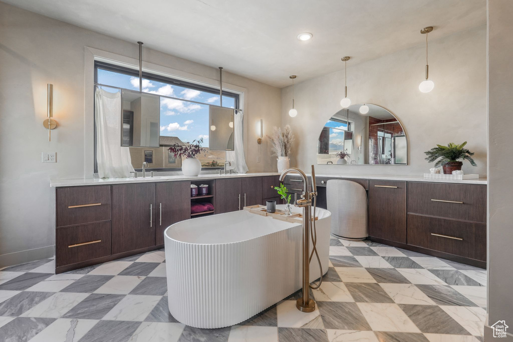 Bathroom with a freestanding bath, vanity, tile patterned floors, and recessed lighting