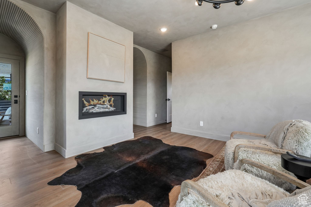 Living room featuring wood finished floors, baseboards, a glass covered fireplace, and recessed lighting