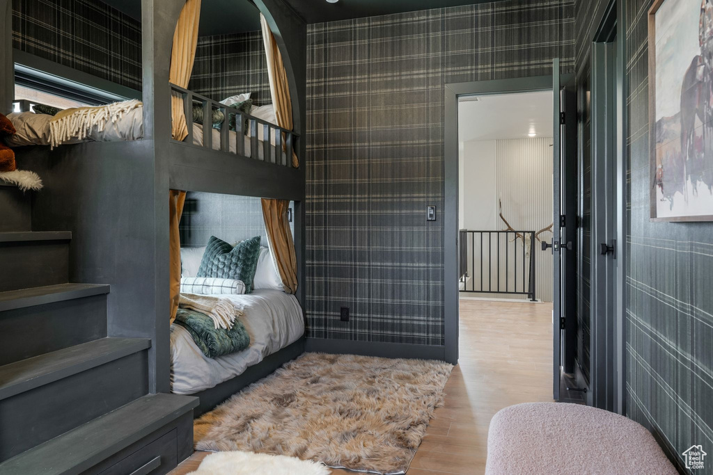 Bedroom featuring wood finished floors and wallpapered walls