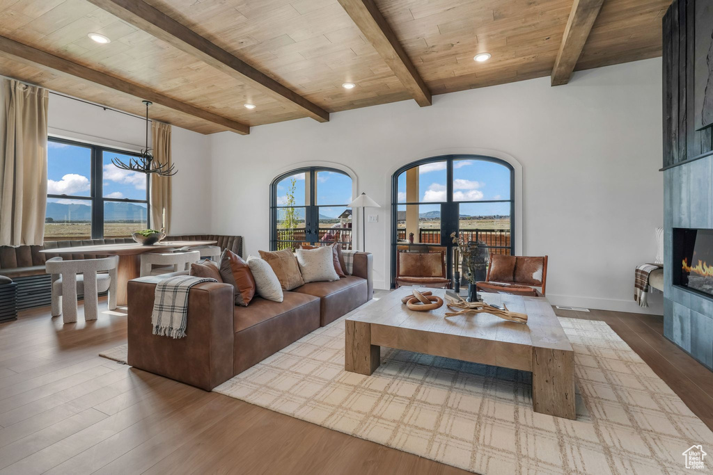 Living area featuring healthy amount of natural light, wood finished floors, a large fireplace, recessed lighting, and a chandelier