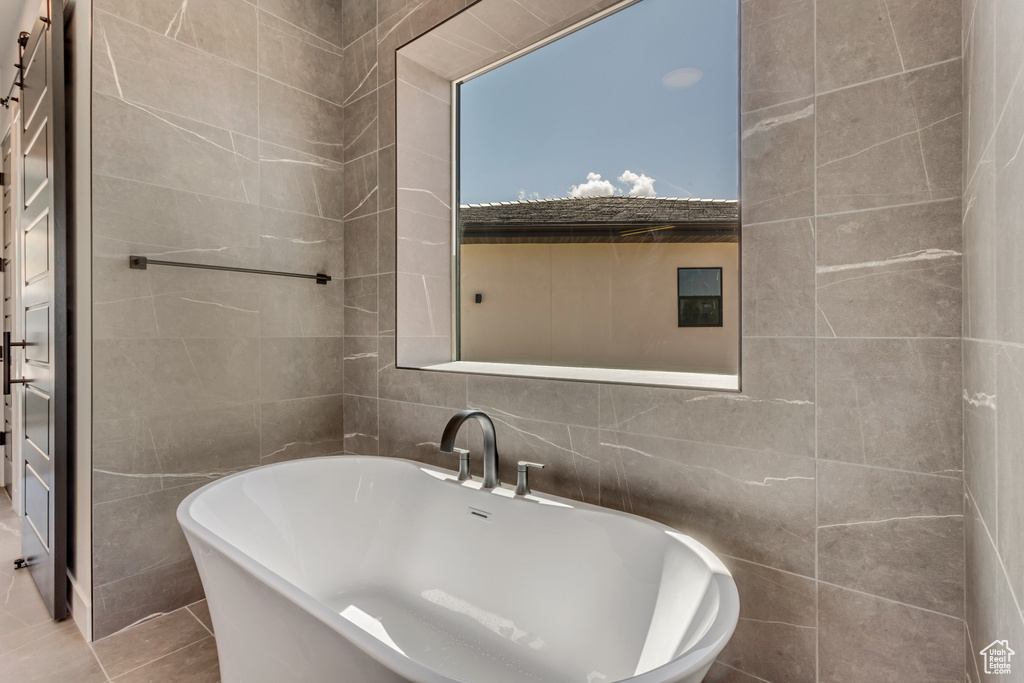 Bathroom with tile walls, a freestanding tub, and tile patterned floors