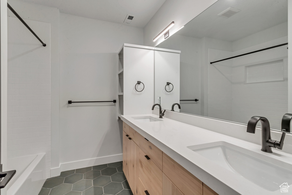 Bathroom with tile patterned flooring, double vanity, washtub / shower combination, and baseboards
