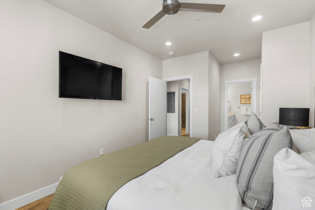 Bedroom with recessed lighting, wood finished floors, electric panel, connected bathroom, and baseboards
