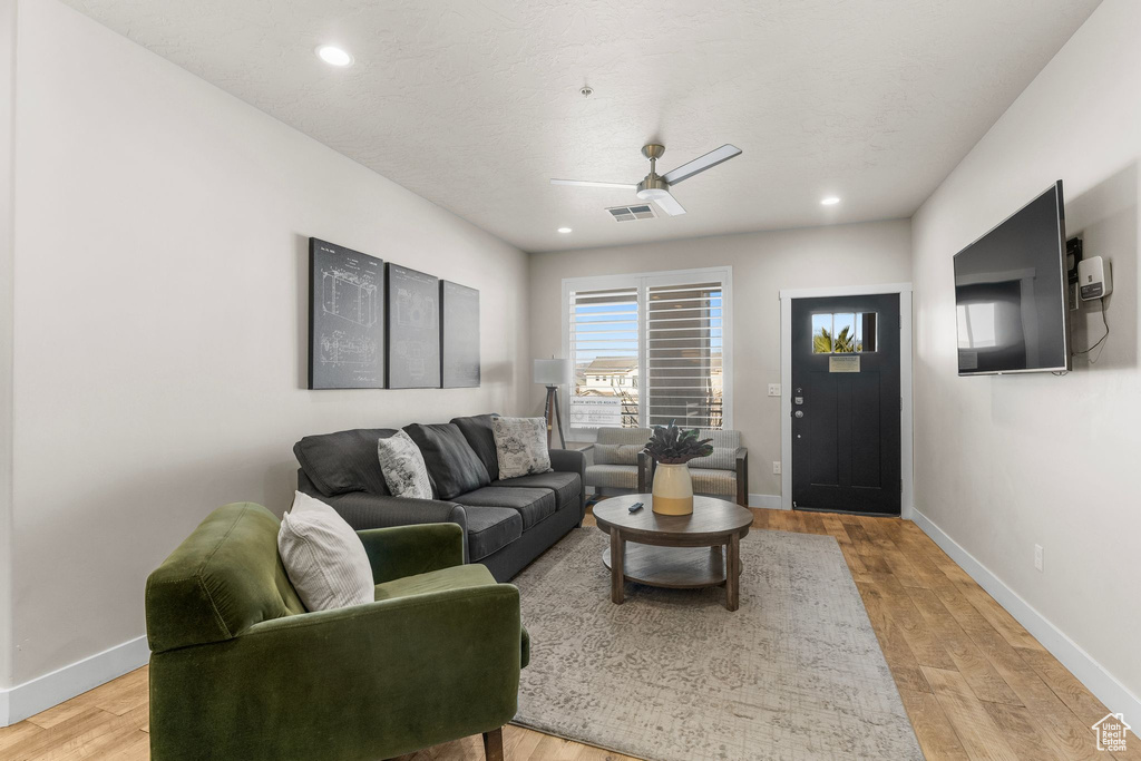 Living area with baseboards, light wood-type flooring, recessed lighting, and a ceiling fan