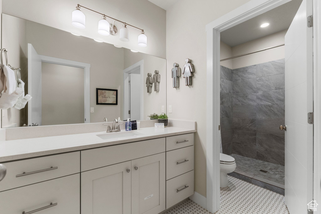 Bathroom featuring vanity, toilet, a tile shower, and baseboards