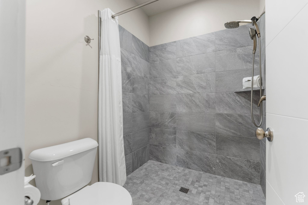 Bathroom featuring a tile shower and toilet