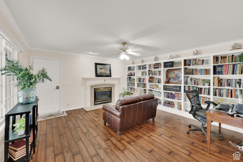 Home office with ornamental molding, a high end fireplace, ceiling fan, hardwood / wood-style flooring, and baseboards