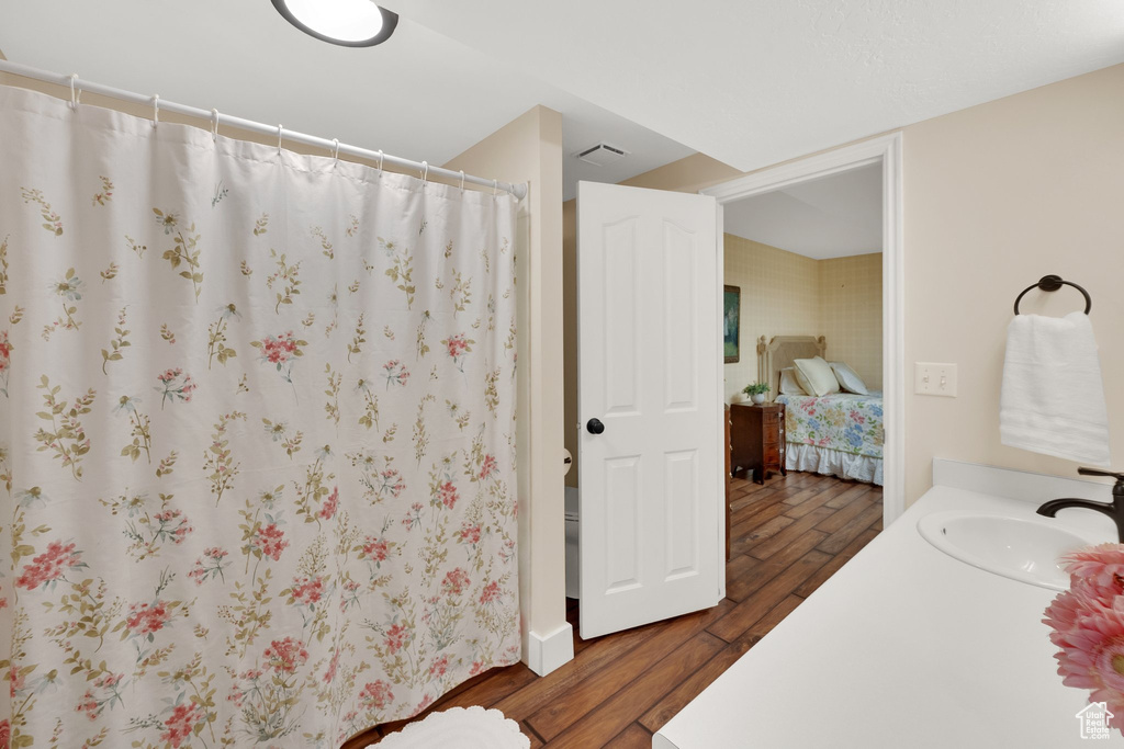 Ensuite bathroom with wood finished floors, vanity, and curtained shower