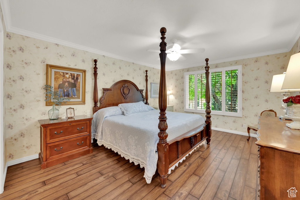 Bedroom featuring wallpapered walls, light wood-type flooring, crown molding, baseboards, and a ceiling fan