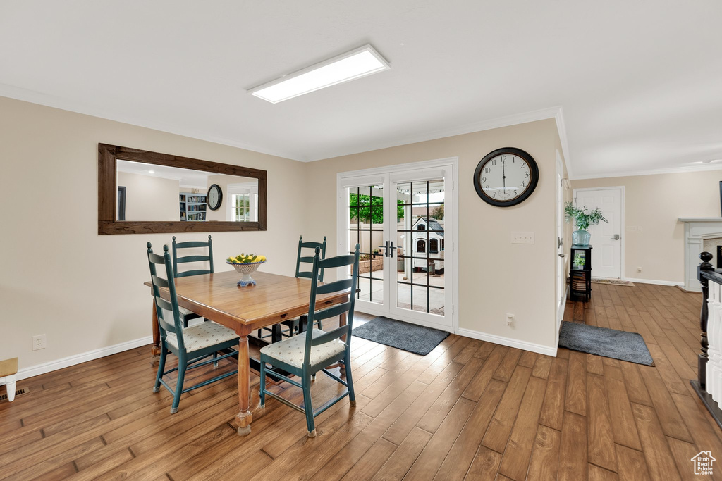 Dining space with wood finished floors, ornamental molding, baseboards, and french doors