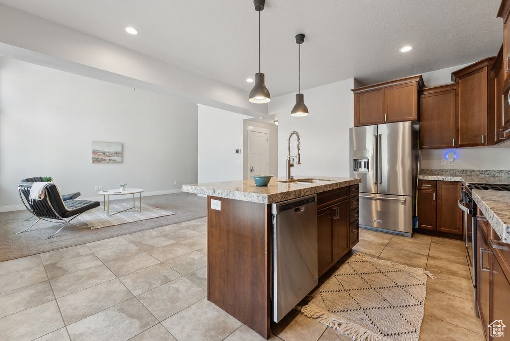 Kitchen featuring appliances with stainless steel finishes, a sink, a kitchen island with sink, recessed lighting, and hanging light fixtures