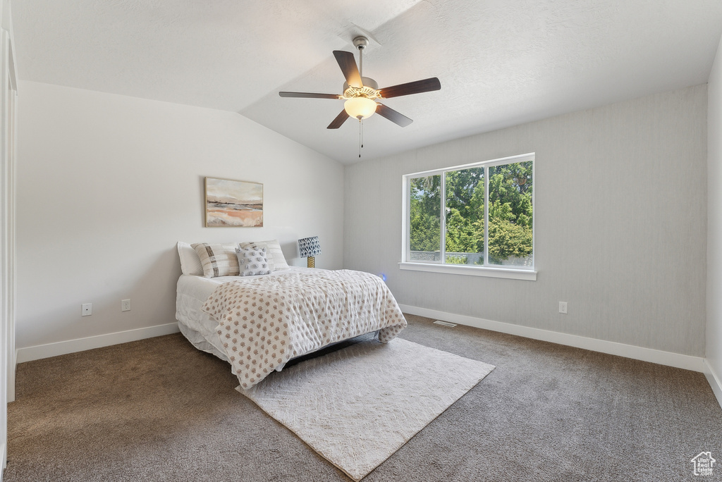 Bedroom featuring carpet floors, baseboards, vaulted ceiling, and ceiling fan