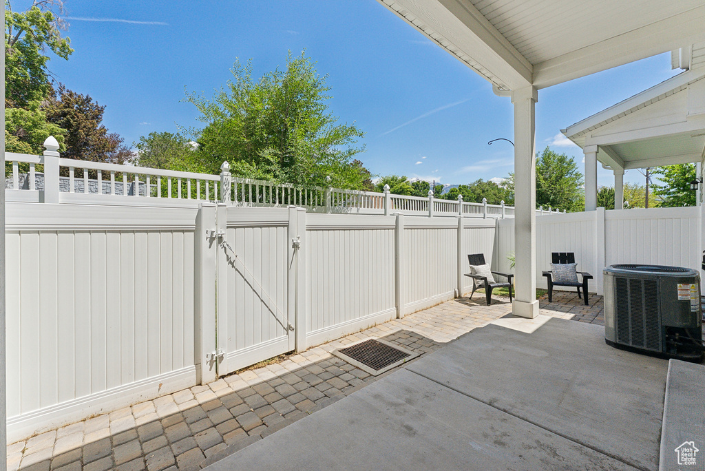 Fenced backyard with central AC unit, a gate, and a patio