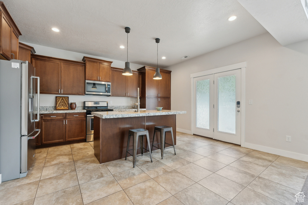 Kitchen with appliances with stainless steel finishes, light tile patterned floors, a center island with sink, recessed lighting, and baseboards