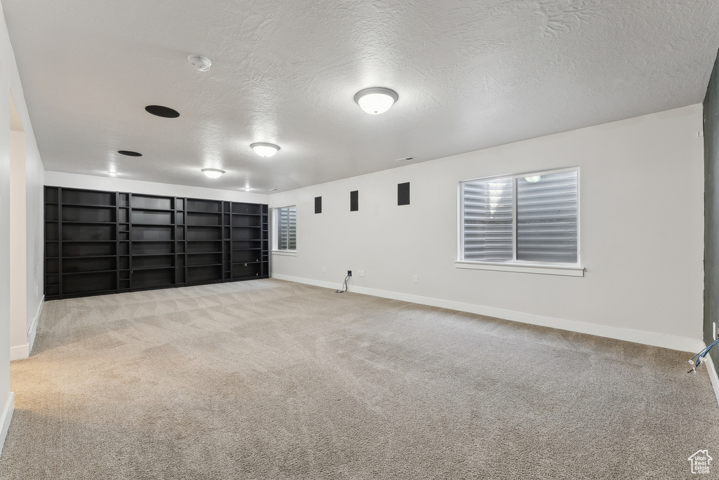 Carpeted empty room with baseboards, a textured ceiling, and built in features