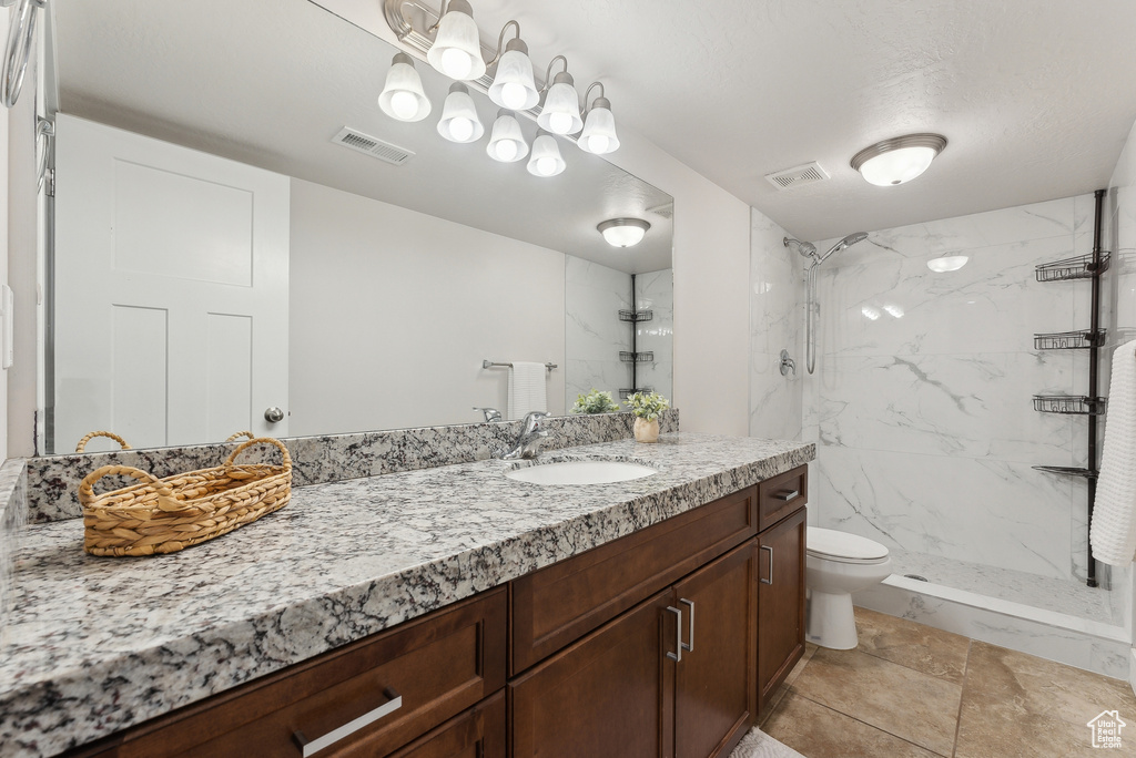 Full bath with toilet, a marble finish shower, and vanity