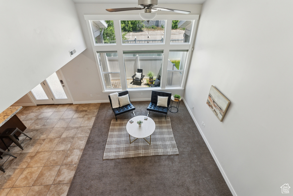 Living area with healthy amount of natural light, a towering ceiling, baseboards, and ceiling fan
