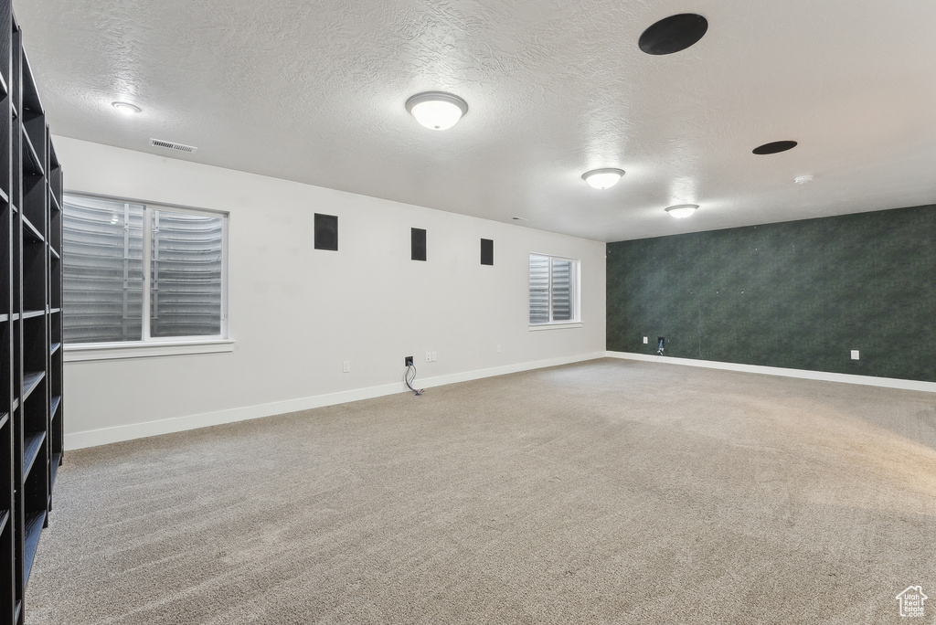 Spare room with carpet, baseboards, and a textured ceiling