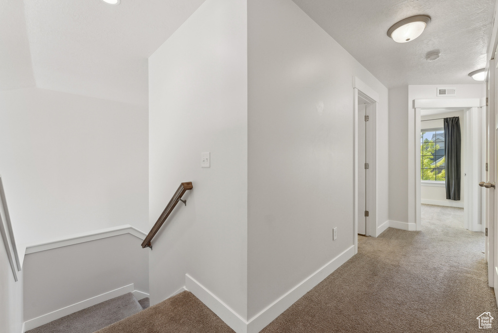 Hall with an upstairs landing, carpet floors, and baseboards