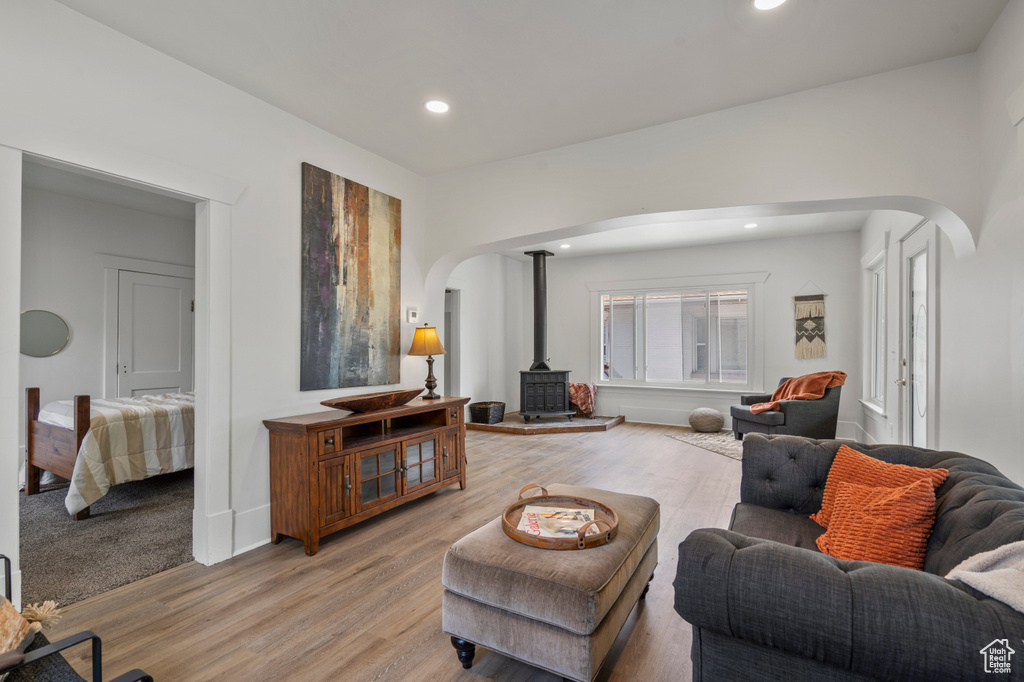 Living area with arched walkways, a wood stove, light wood-type flooring, recessed lighting, and baseboards