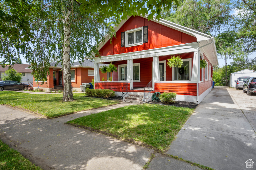 View of front of house with covered porch and a front yard