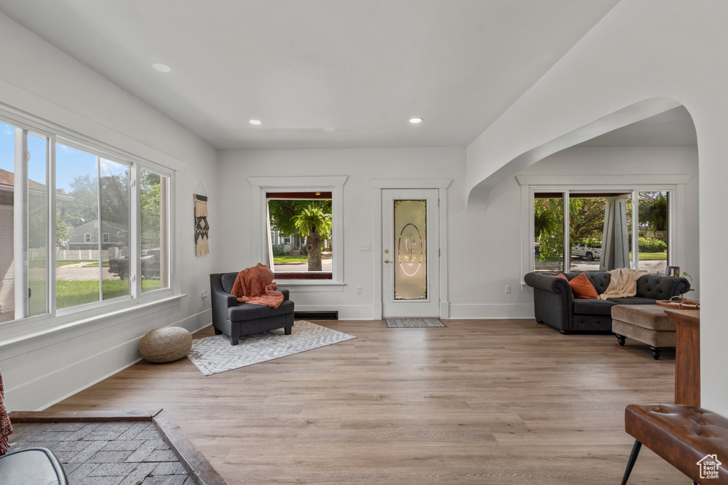 Foyer with arched walkways, light wood finished floors, recessed lighting, and baseboards