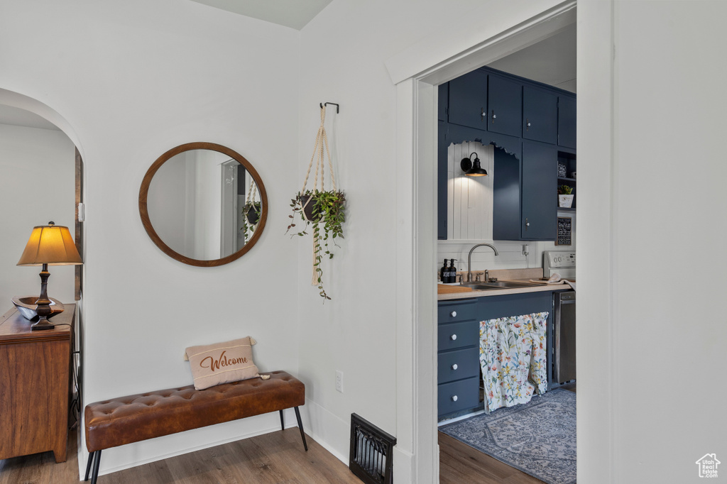 Hall featuring a sink, wood finished floors, arched walkways, and baseboards