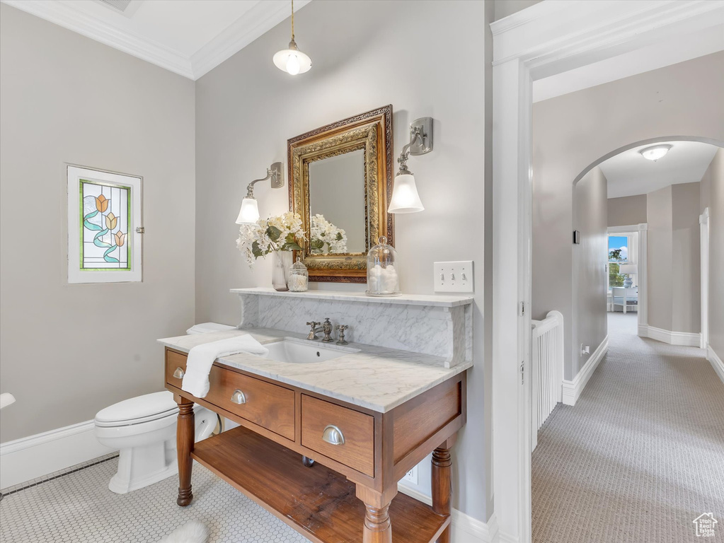 Half bath with vanity, toilet, baseboards, and crown molding