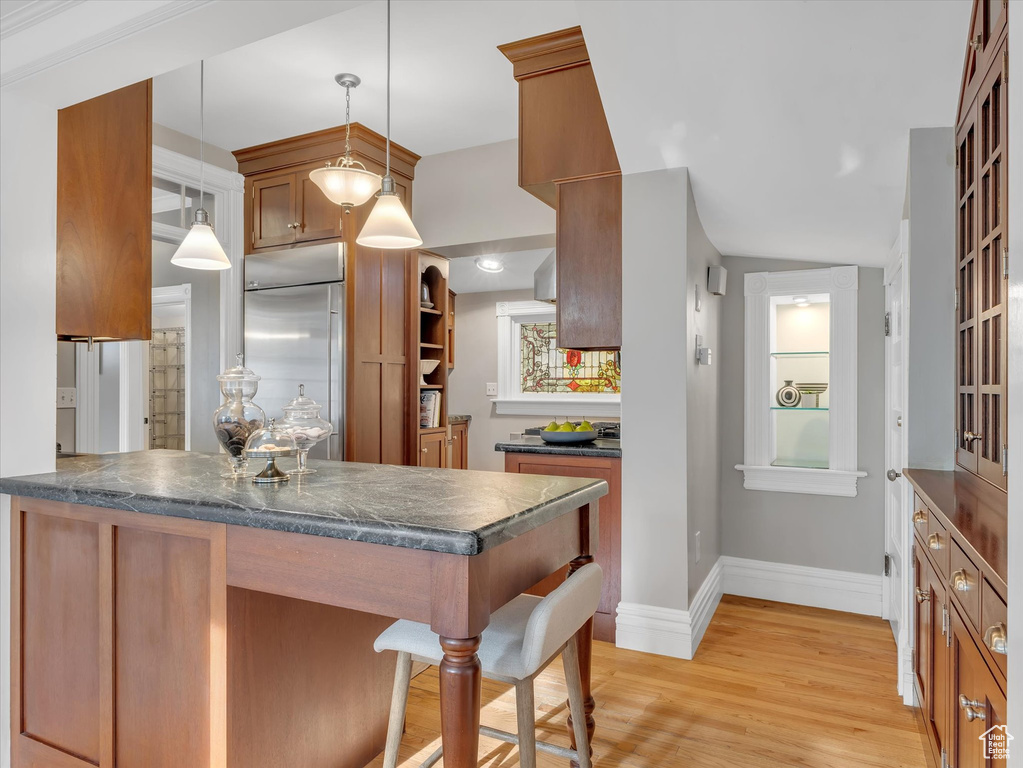 Kitchen with built in fridge, dark countertops, brown cabinetry, and baseboards