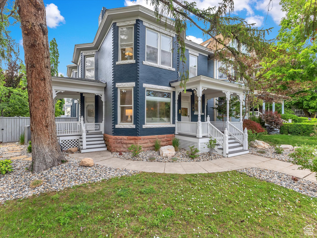 Victorian-style house with a porch and a front lawn