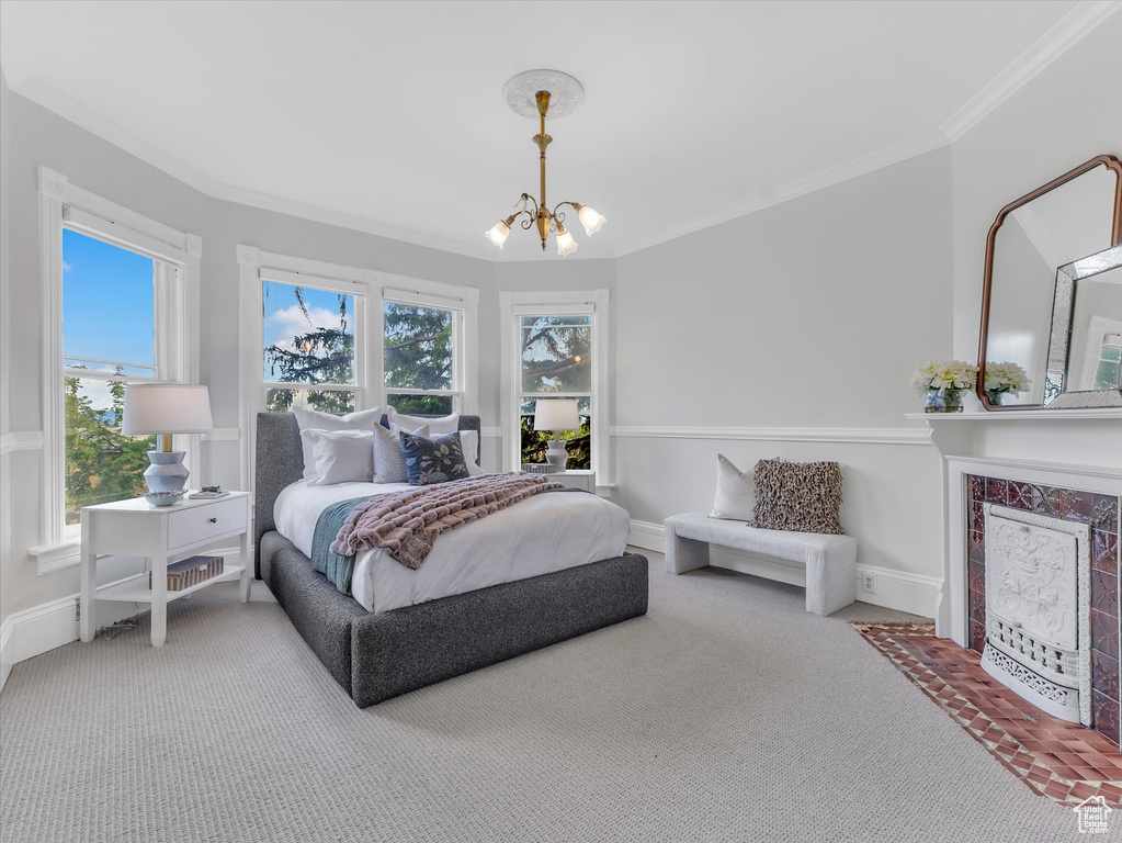Carpeted bedroom with a chandelier, crown molding, a tile fireplace, and baseboards