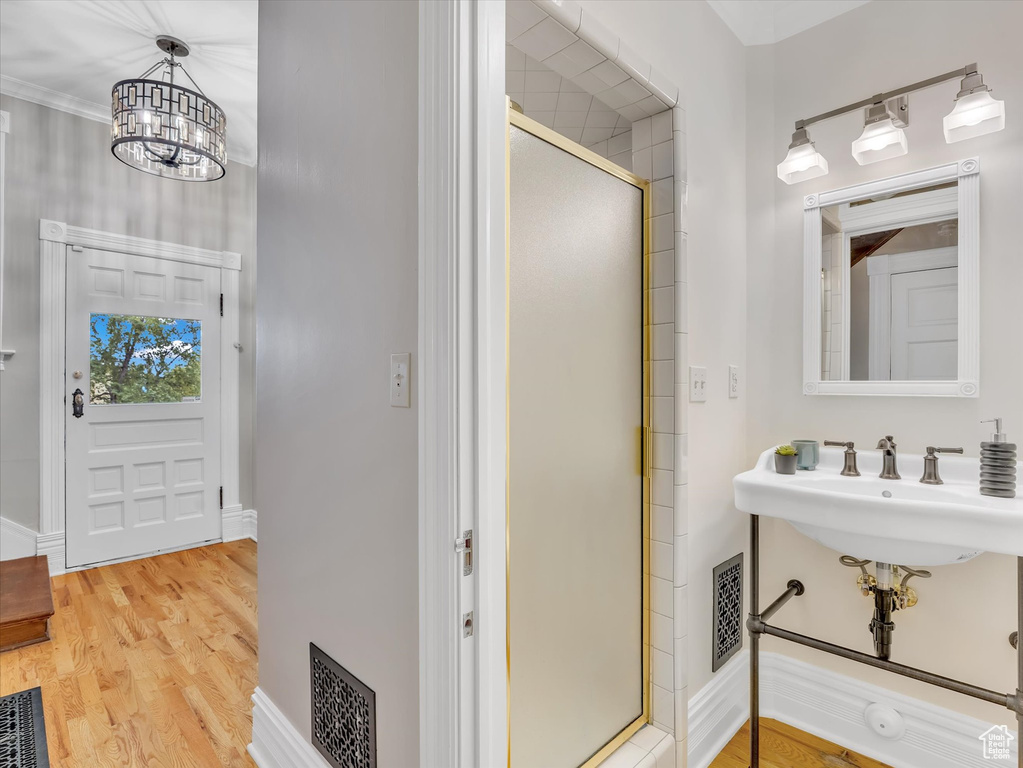 Bathroom with a stall shower, a chandelier, wood finished floors, and baseboards