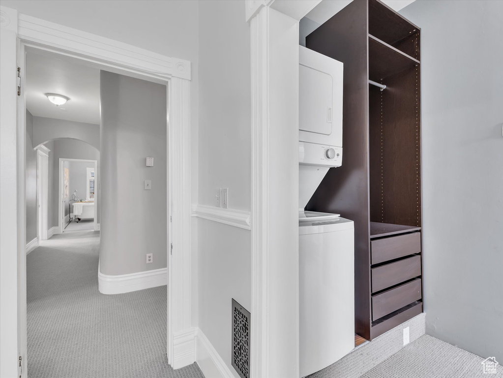 Laundry area featuring stacked washer / dryer, arched walkways, and carpet flooring
