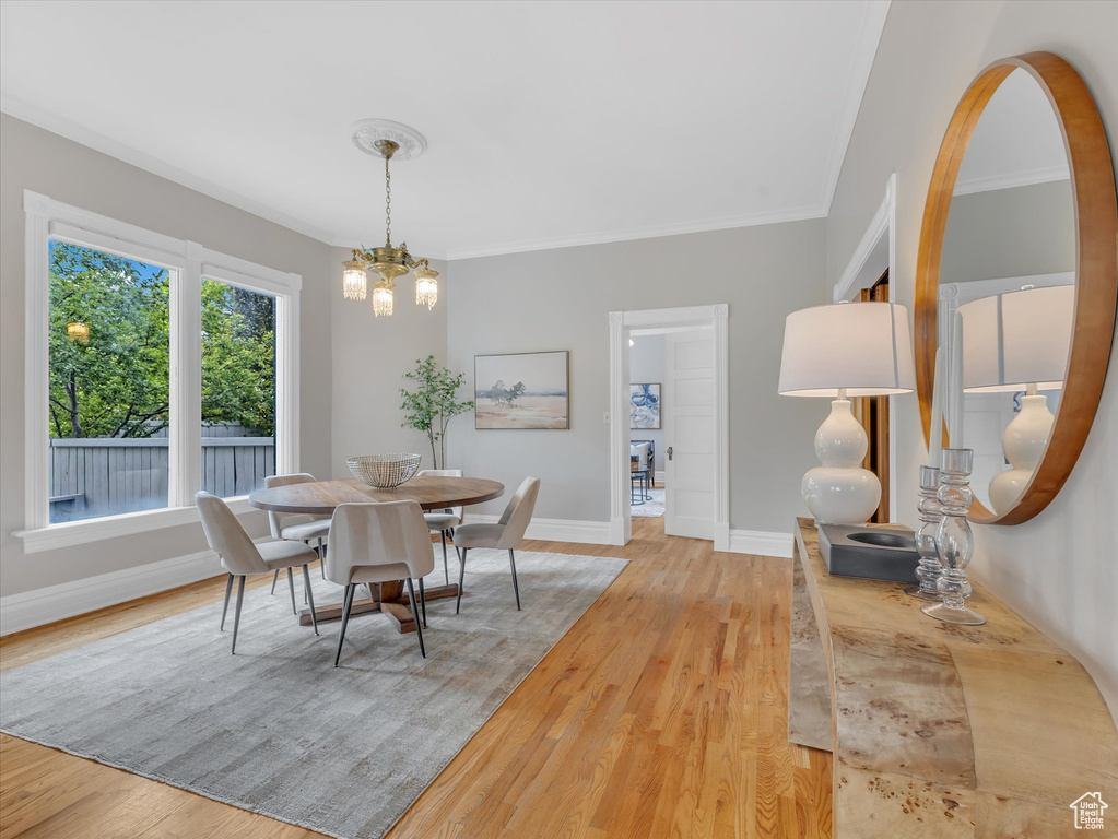 Dining room with light wood-type flooring, baseboards, a chandelier, and ornamental molding