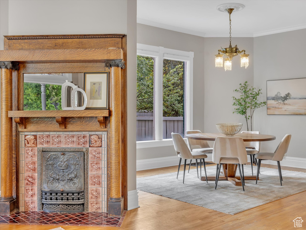 Dining area with a chandelier, wood finished floors, baseboards, and ornamental molding