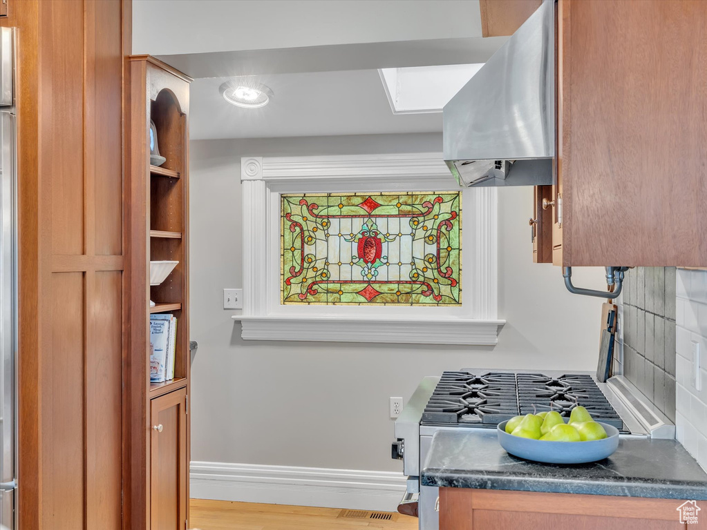 Kitchen with range hood, dark countertops, baseboards, and tasteful backsplash