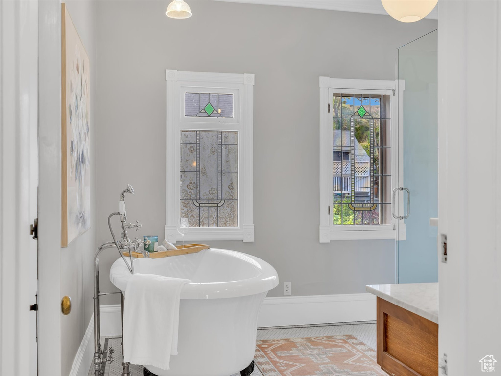 Bathroom with a soaking tub, baseboards, and vanity