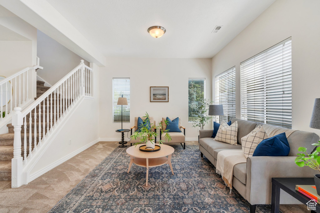 Carpeted living room featuring stairway and baseboards