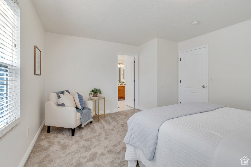 Bedroom with light carpet, baseboards, and ensuite bathroom