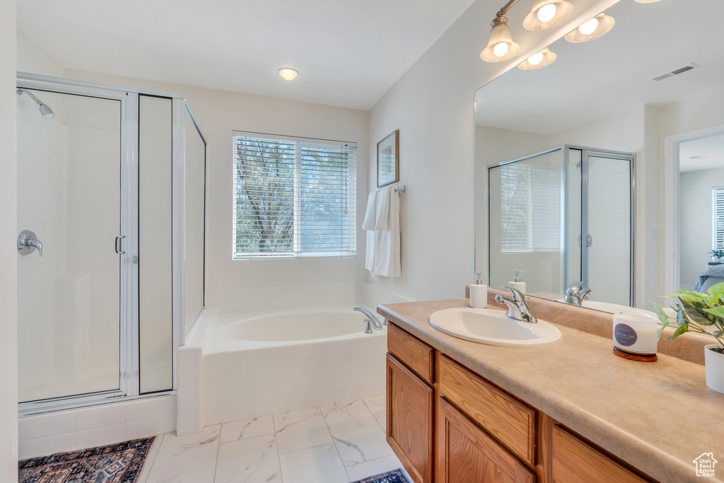 Bathroom with a shower stall, vanity, marble look tiles, and a bath