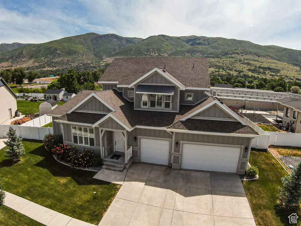 View of front of home featuring board and batten siding, roof with shingles, concrete driveway, and a mountain view