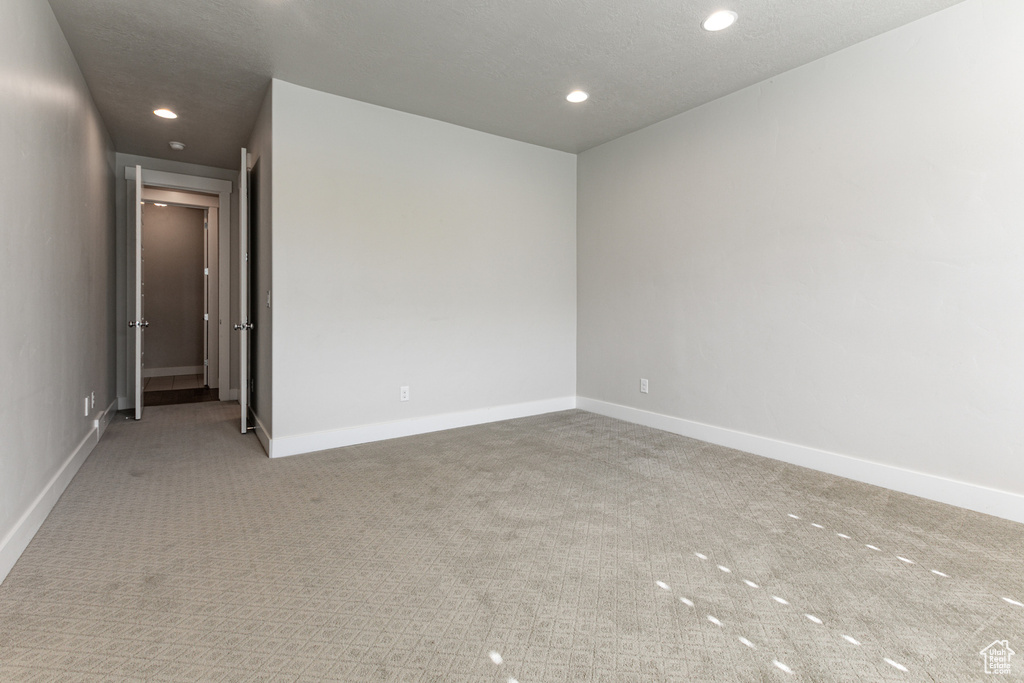 Carpeted empty room with baseboards and recessed lighting