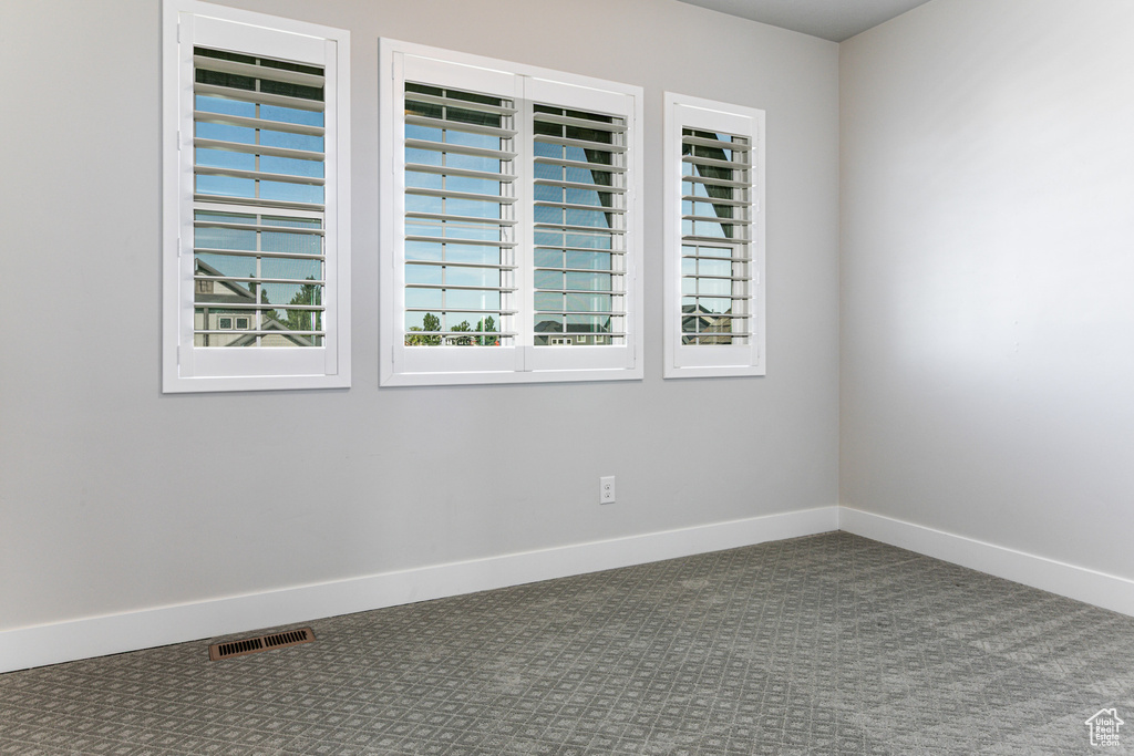 Carpeted spare room featuring baseboards